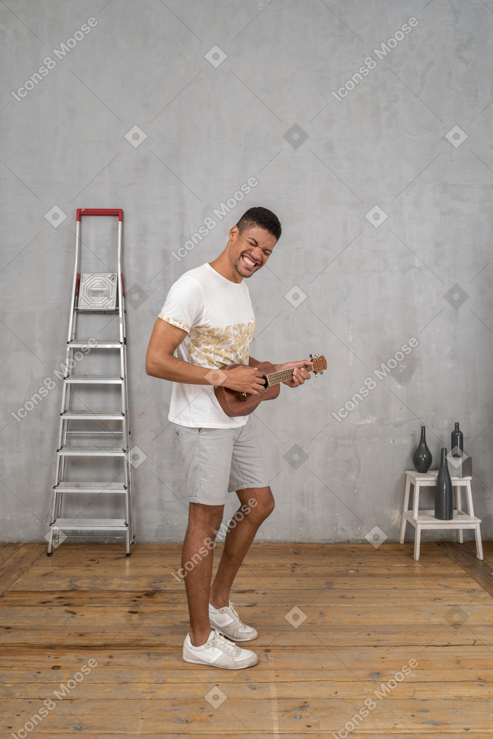 Vista lateral de um homem tocando cavaquinho e sorrindo