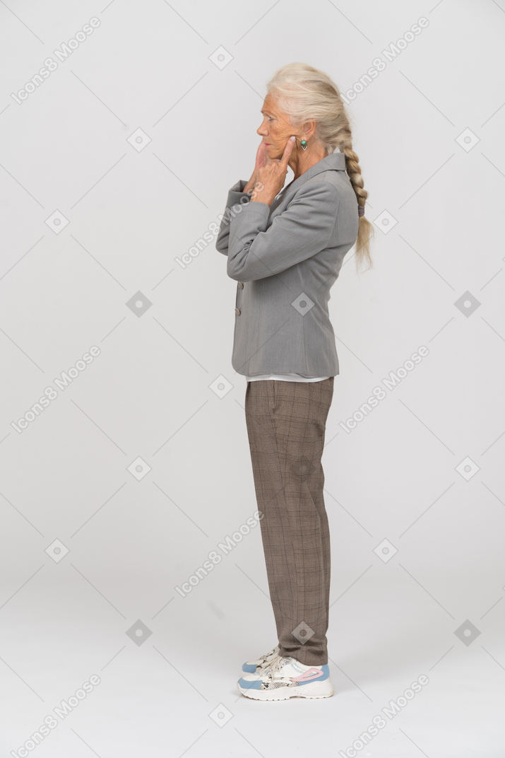 Side view of an old lady in suit touching her face