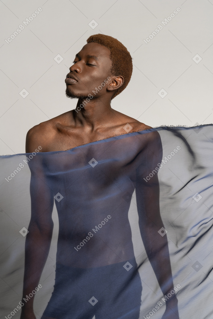 Vista frontal de un joven afro de pie con un chal azul oscuro