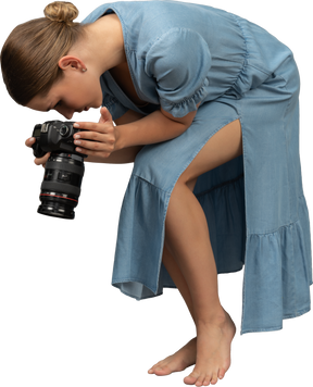 Трехчетвертный вид молодой женщины в синем платье, делающей выстрел