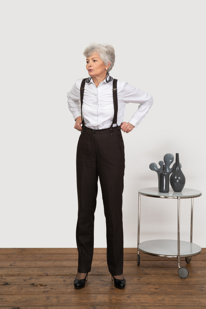 Front view of an old lady in office clothing adjusting her trousers