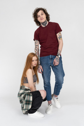 Teenage boy posing with his girlfriend squatting by his side