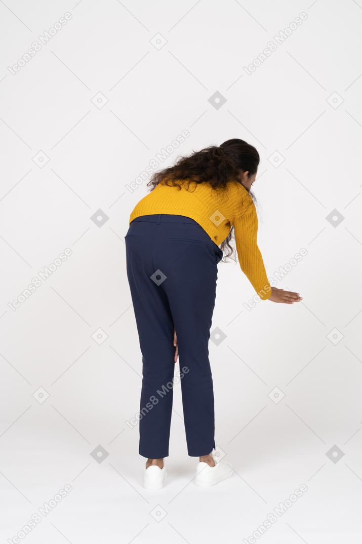 Rear view of a girl in casual clothes bending down with extended hand