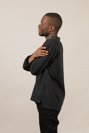 Side view of young man hugging himself