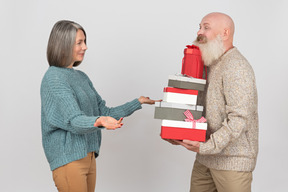 Hombre de edad dando regalos a una mujer madura elegante