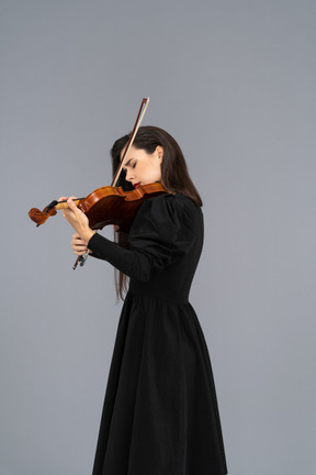 Close-up de uma jovem de vestido preto tocando violino