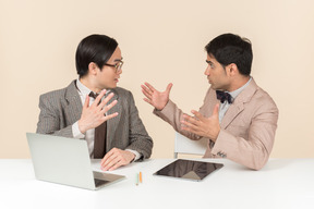 Deux jeunes nerds assis à la table avec des gadgets dessus et comprendre quelque chose