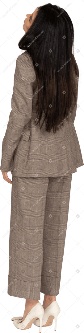 Three-quarter back view of a young lady in brown business suit throwing head back