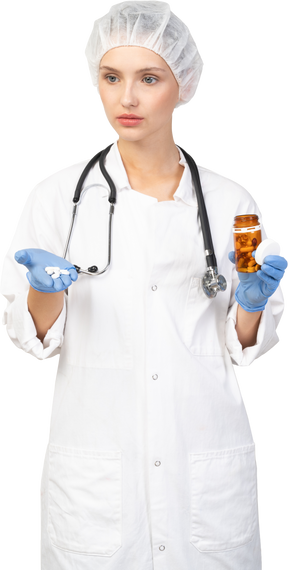 Vista frontal de una joven doctora sosteniendo pastillas