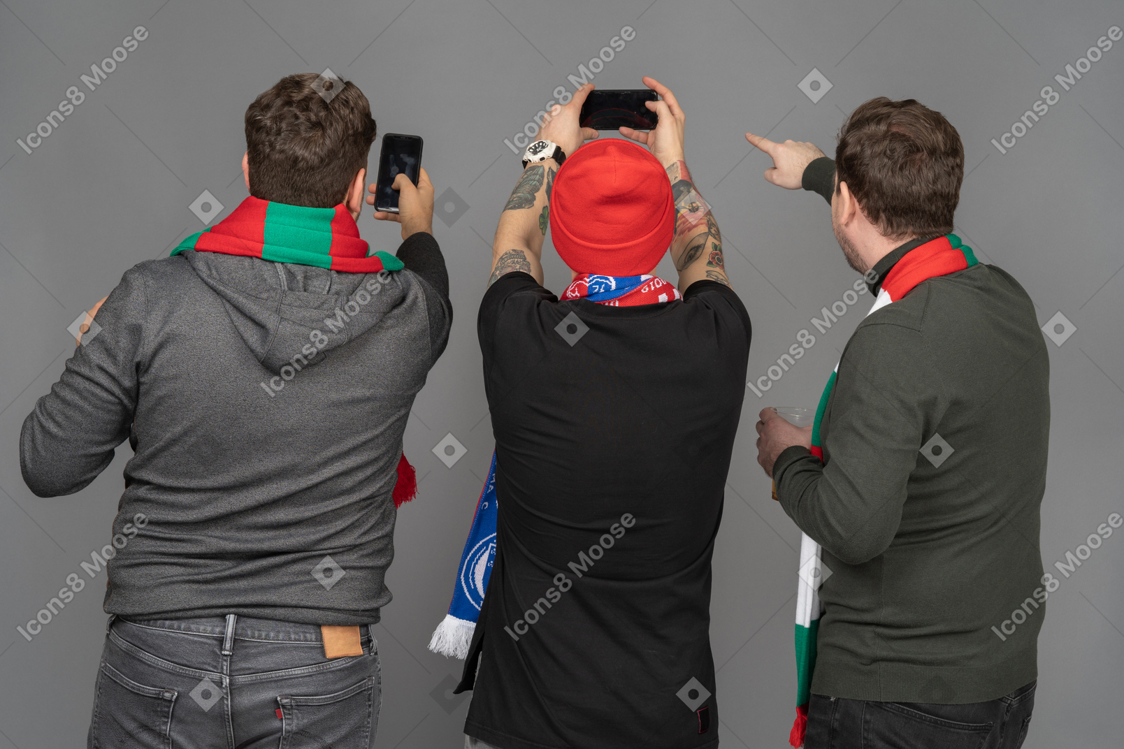 Vista posteriore di tre tifosi di calcio di sesso maschile che scattano foto con il telefono