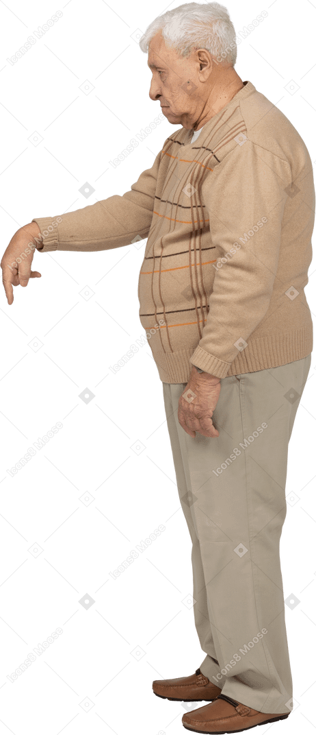 Side view of an old man in casual clothes pointing down with finger