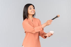 Indian woman holding face powder and powder brush