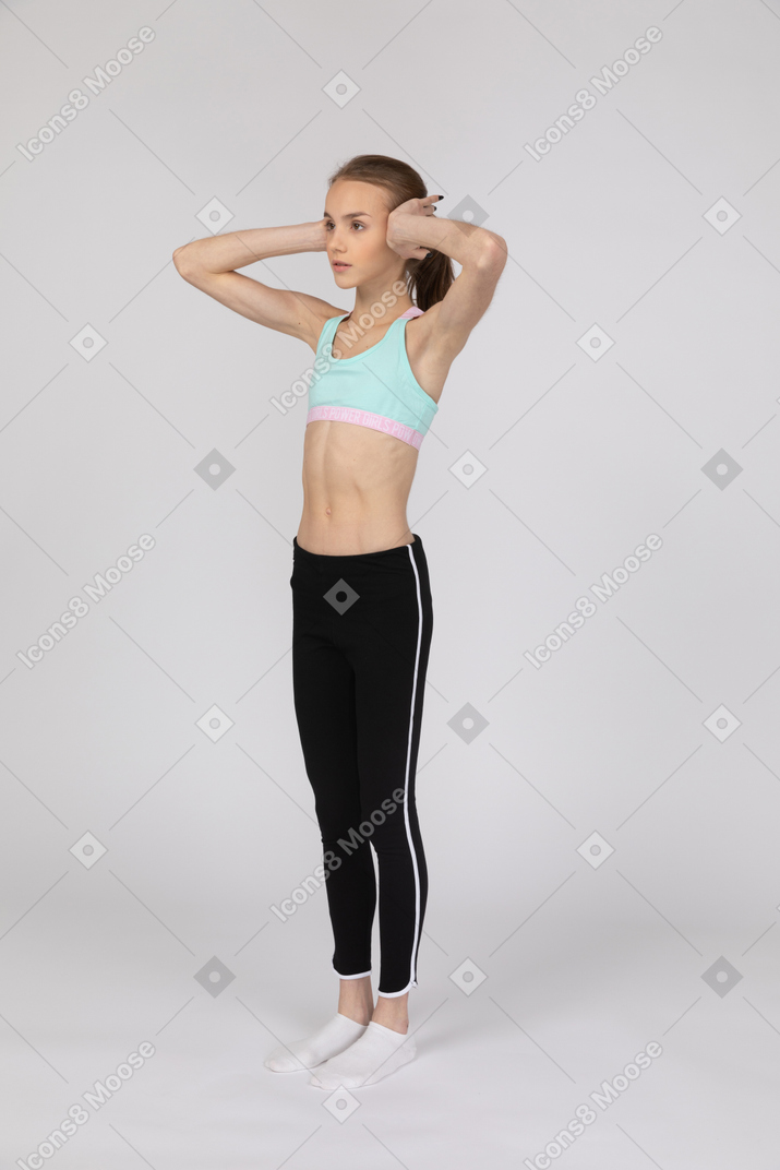 Una adolescente con ropa deportiva tapándose los oídos con las manos.