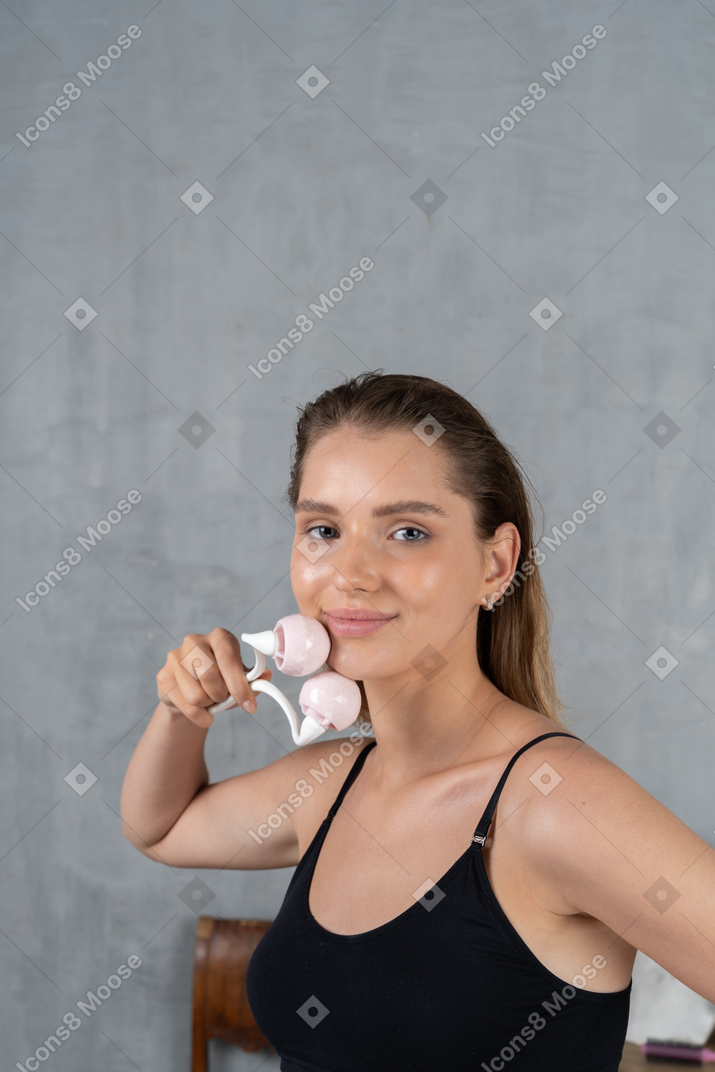Portrait of a young woman massaging her face with face roller