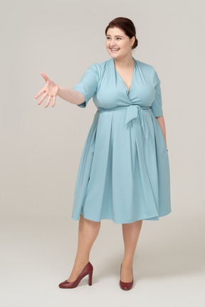 Vista frontal de una mujer en vestido azul dando la mano para un apretón