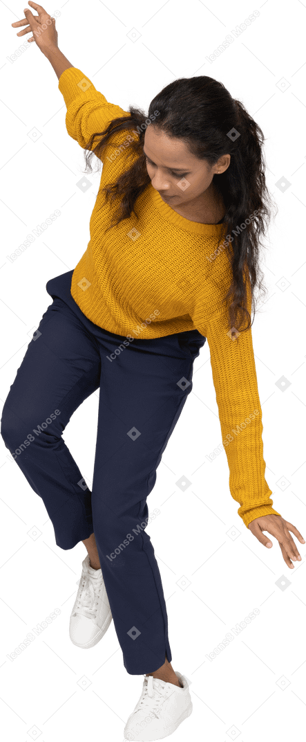 Vue de face d'une fille en vêtements décontractés posant sur une jambe avec les bras tendus