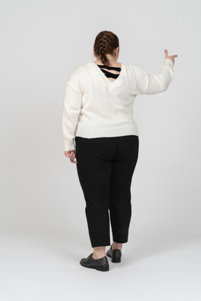 Vista posteriore di una donna grassoccia in abiti casual che indica con un dito