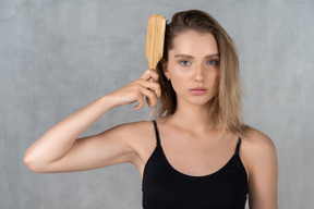 Close-up of a young woman brushing top of her head