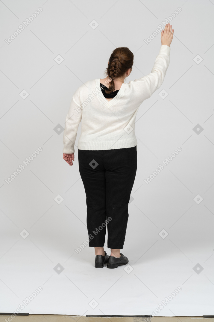 Rear view of a plump woman in casual clothes greeting someone