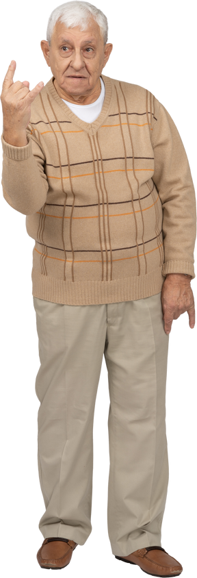 Vista frontale di un uomo anziano in abiti casual che mostra un gesto rock