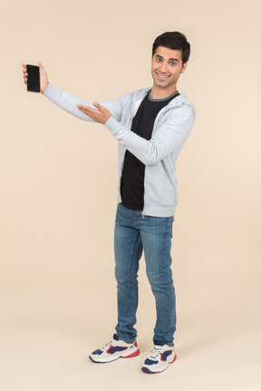 Joven caucásico que presenta smartphone