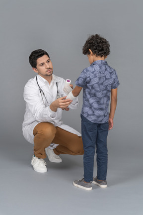 Médecin bandant la main d'un garçon