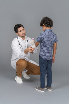 Médico enfaixando a mão de um menino