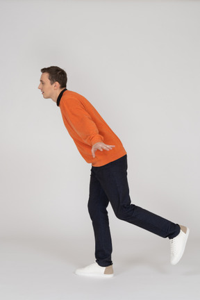 Junger mann im orange sweatshirt springen
