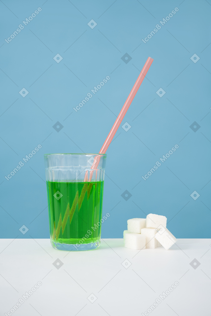 緑色の液体と砂糖の立方体を持つガラス