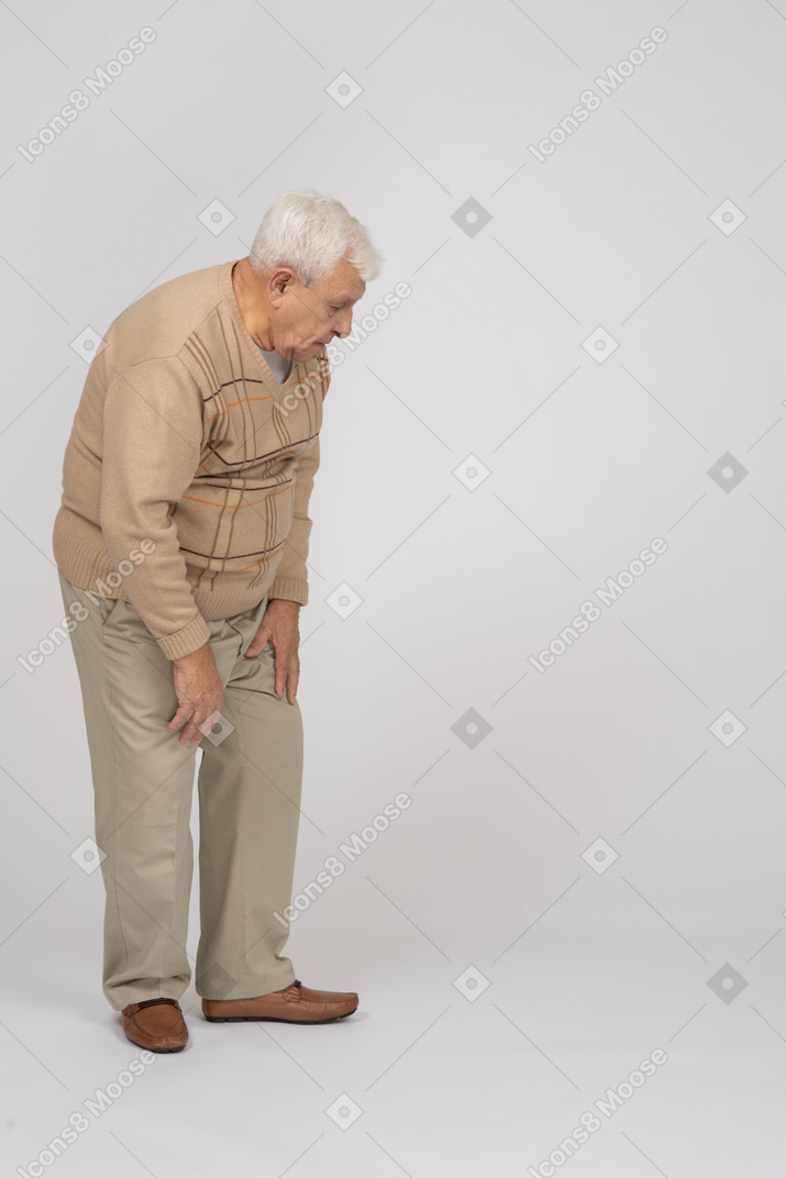 Seitenansicht eines alten mannes in freizeitkleidung, der sich nach unten beugt