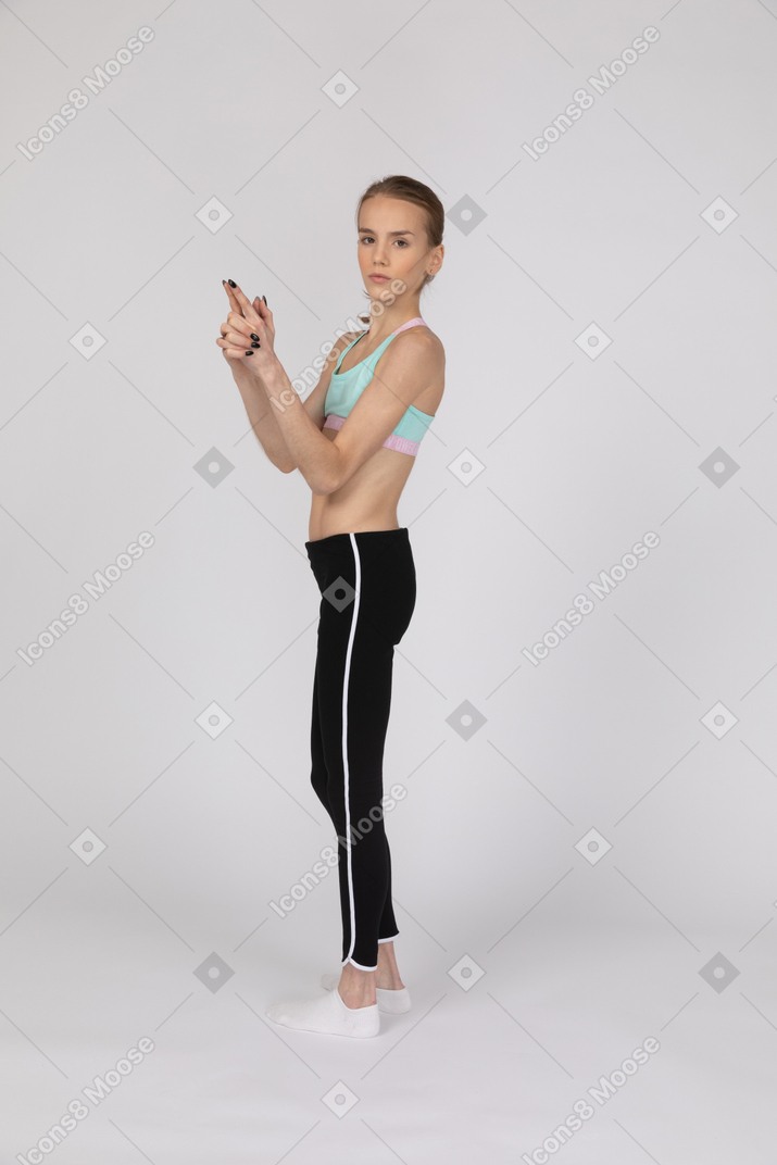 Menina adolescente em roupas esportivas fazendo gesto de arma de dedo