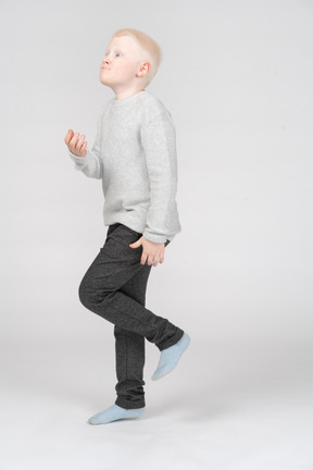 Three-quarter view of a boy standing on one leg