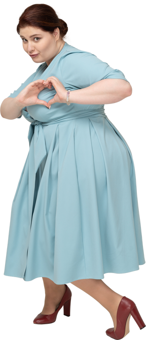 Вид сбоку женщины в синем платье, показывающей жест сердца