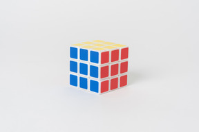 Un cubo de rubik resuelto rompecabezas acostado sobre un fondo blanco liso