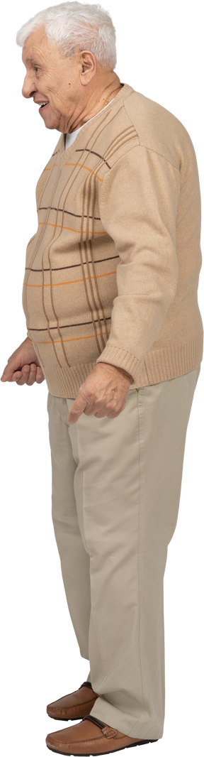 Side view of a happy old man in casual clothes standing with clenched fists