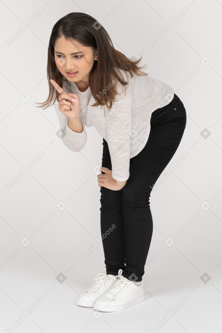 Side view of a young indian female in casual clothes leaning on arms & bending knees