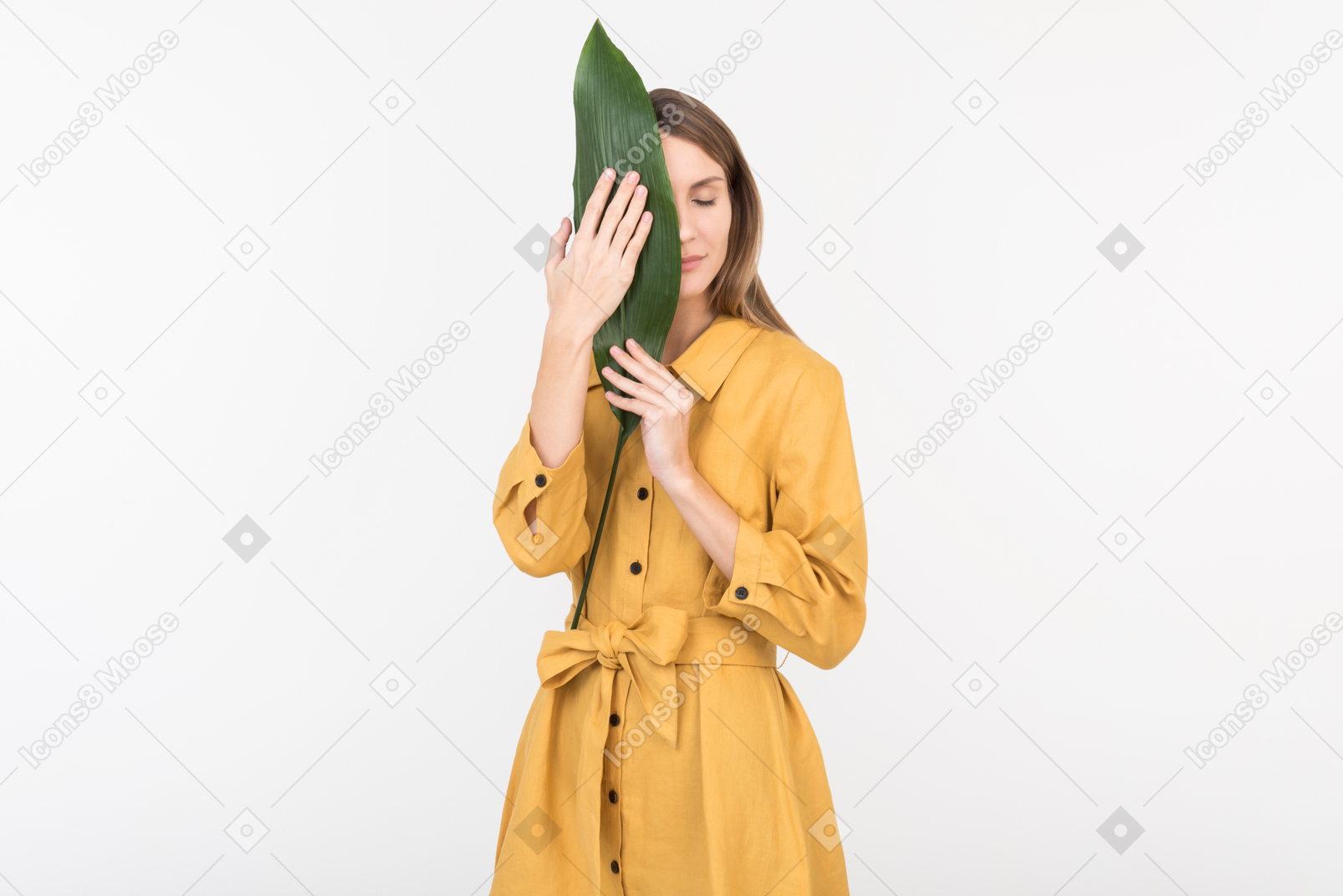 Young woman closing her face with green leaf with eyes closed