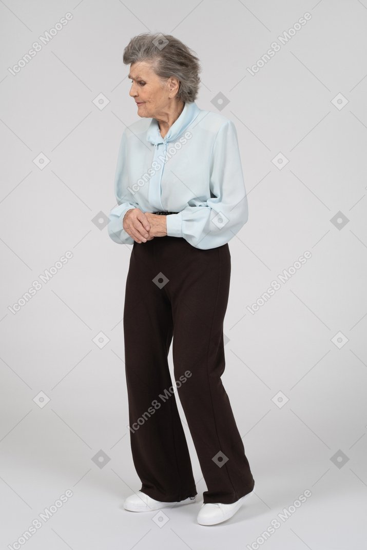 Vista di tre quarti di una donna anziana che guarda in basso con le mani giunte