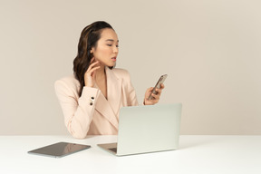 Empleado de oficina femenino asiático comprobando teléfono