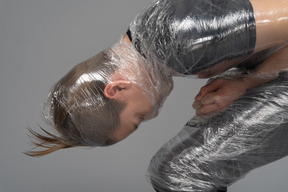 Young man on his knees wrapped in plastic