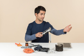 A young man in casual blue clothes working with computer details