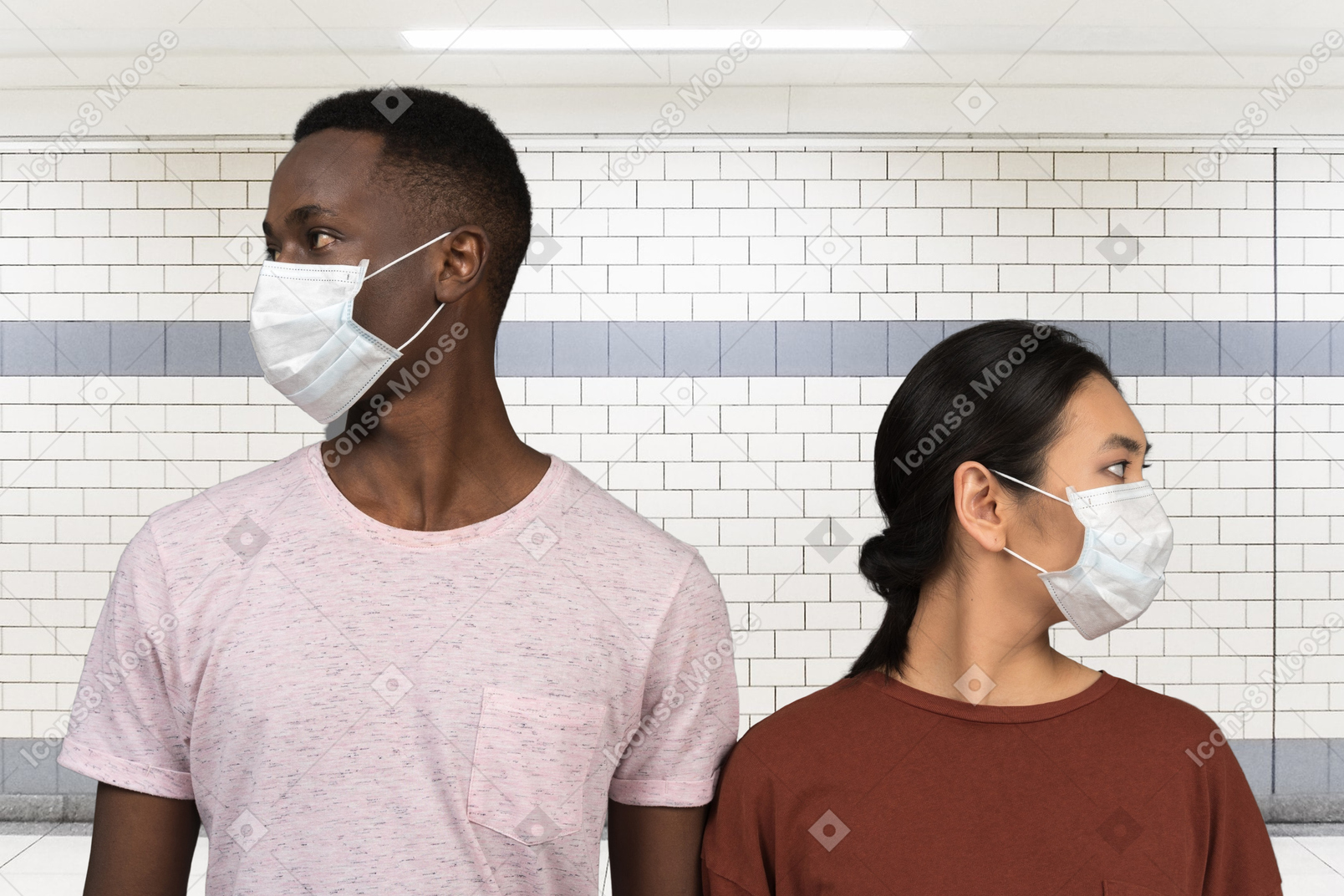 Joven pareja interracial con máscaras médicas y mirando a un lado