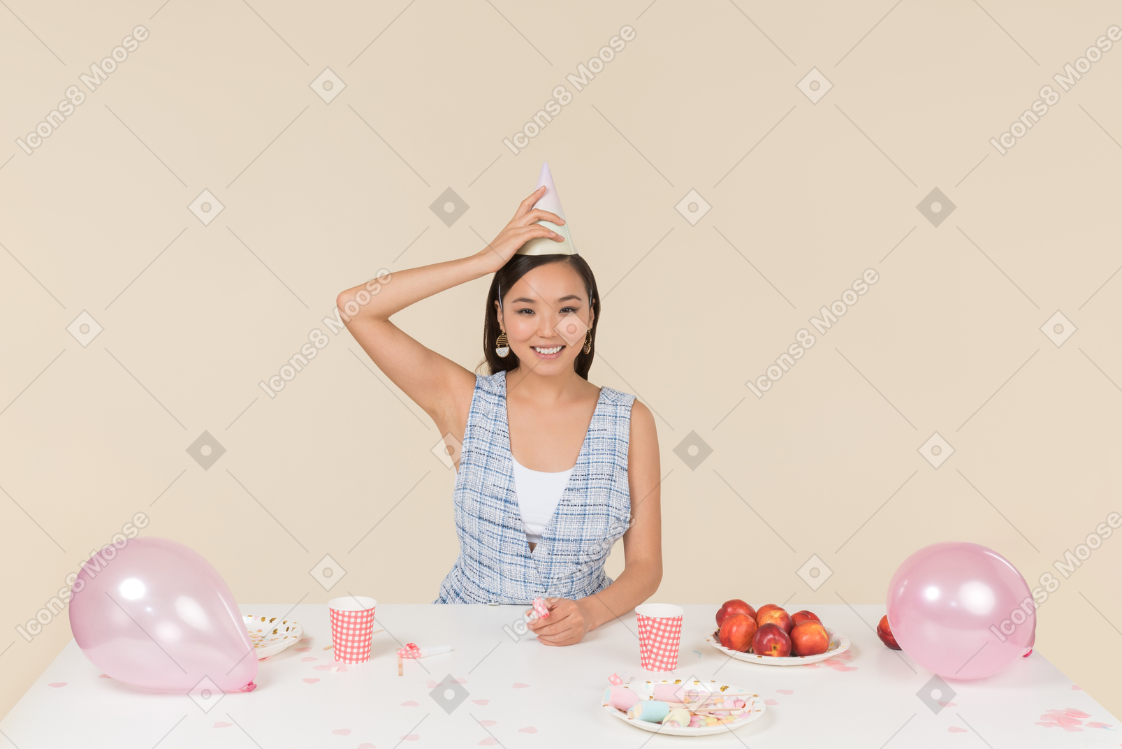 Joven asiática ajustando el cono de cumpleaños en la cabeza