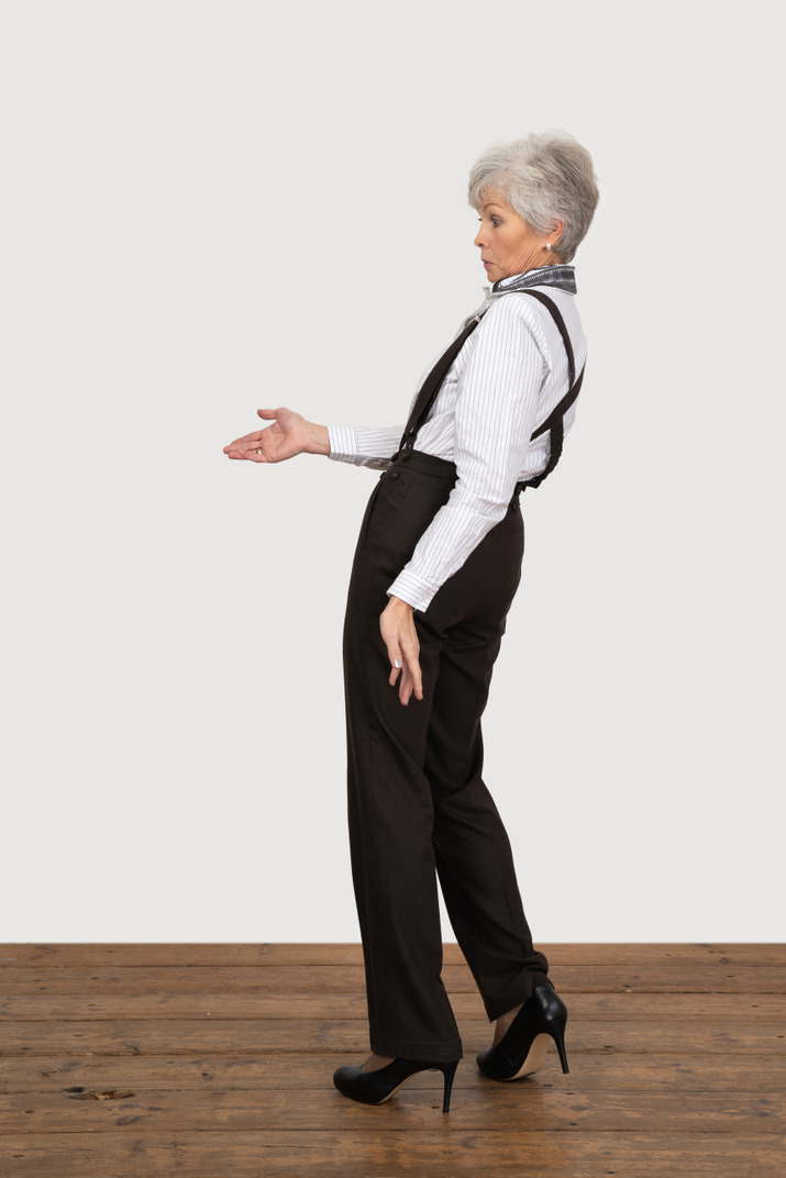 Side view of a questioning old lady in office clothing outstretching her hand