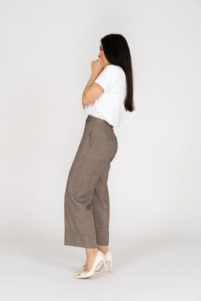Side view of a scared young lady in breeches and t-shirt touching her mouth