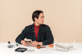 An asian geek guy in a dark checkered shirt, working with computer details