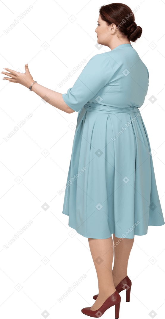 Женщина в синем платье жестикулирует, вид сбоку