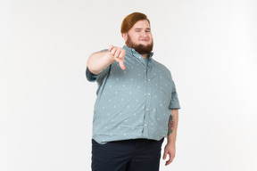 Dissatisfied young overweight man showing thumbs down