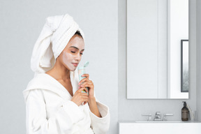 A woman with a towel on her head doing her skincare