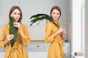 A woman in a yellow robe holding a green plant